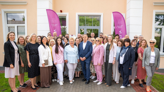 Pasākuma dalībnieku kopīga fotogrāfija pie Rēzeknes biroja ieejas, fonā divi violeti Valsts zemes dienesta karogi